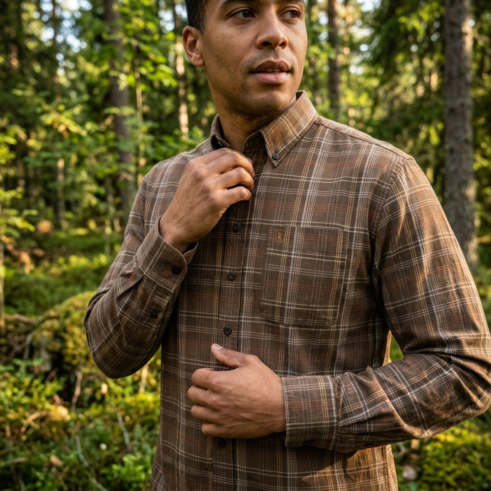 Man wearing a brown plaid shirt in a forest setting